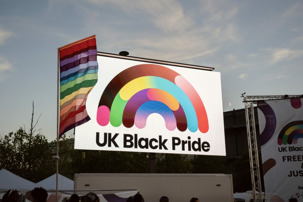 UK Black Pride logo behind a rainbow flag