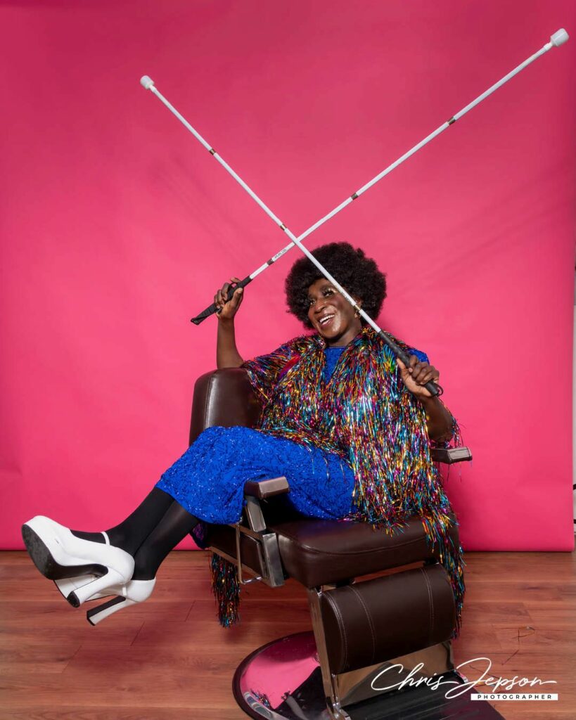 A person wearing colourful knitwear sitting in a barber's chair