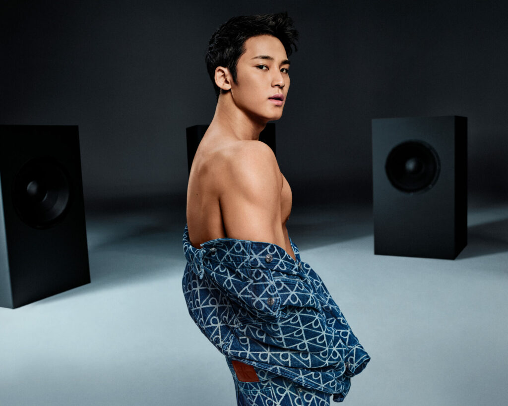 K-pop star Mingyu stars in Calvin Klein's fall 2025 denim campaign wearing an all-over graphic CK Emblem denim jacket over his shoulders to reveal his muscles.