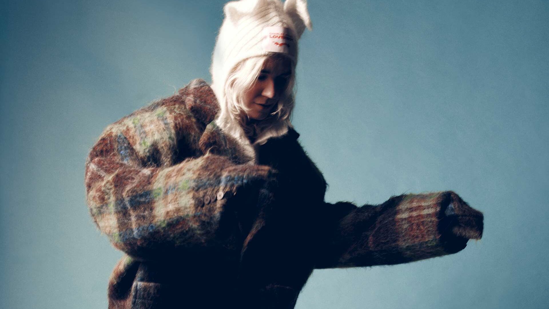 HAAI in a brown tartan wool coat with blond hair