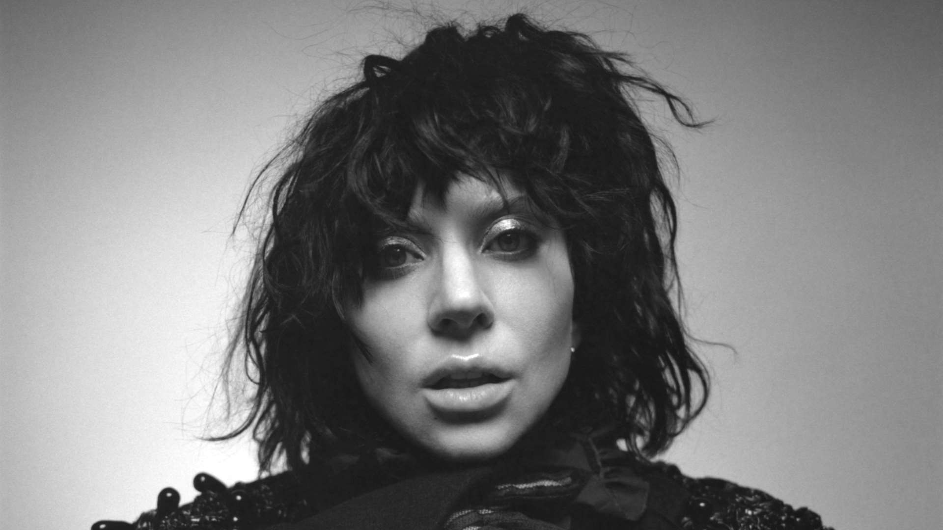 Lady Gaga with messy black hair poses for black-and-white image.