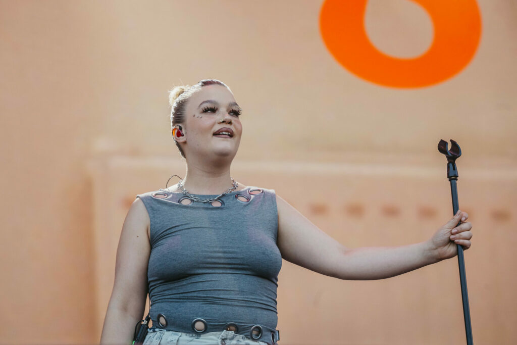 Lola Young at Flow Festival 2025 in a grey top holding a mic stand