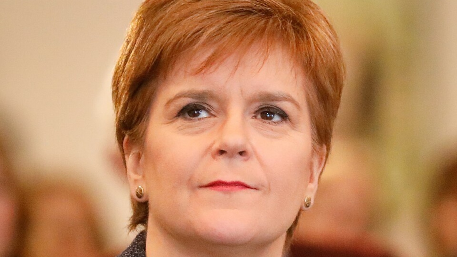 Nicola Sturgeon headshot looking to the top left of the screen in bright pink lipstick