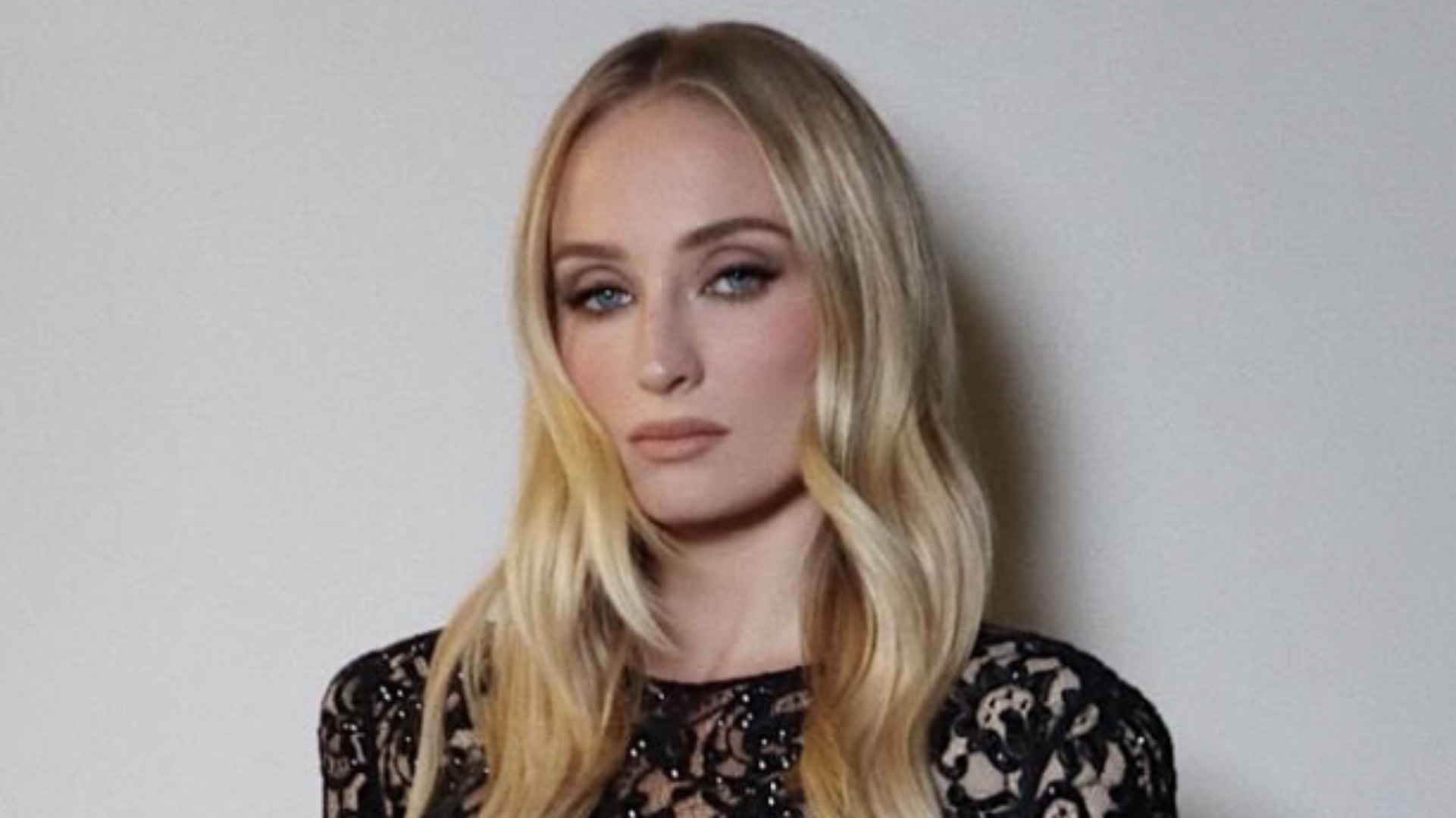 Sophie Turner wearing a black lace dress and dark eye makeup