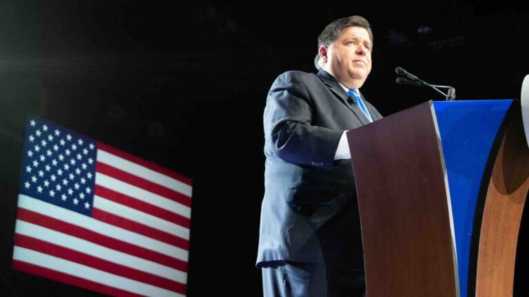 Governor JB Pritzker posed against U.S. flag