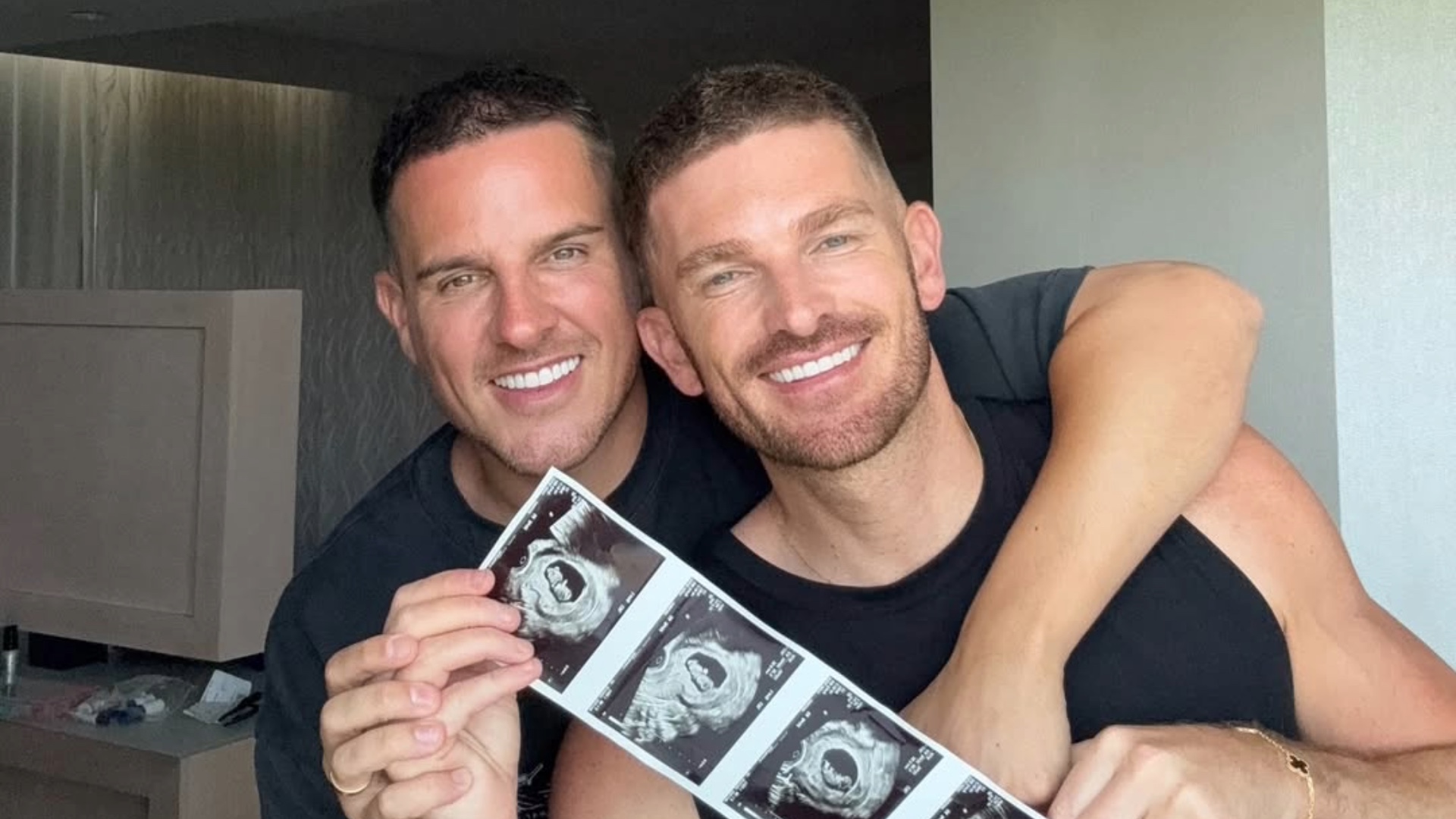 Adam Frisby and his fiancé Jamie Corbett pose with ultrasound scans