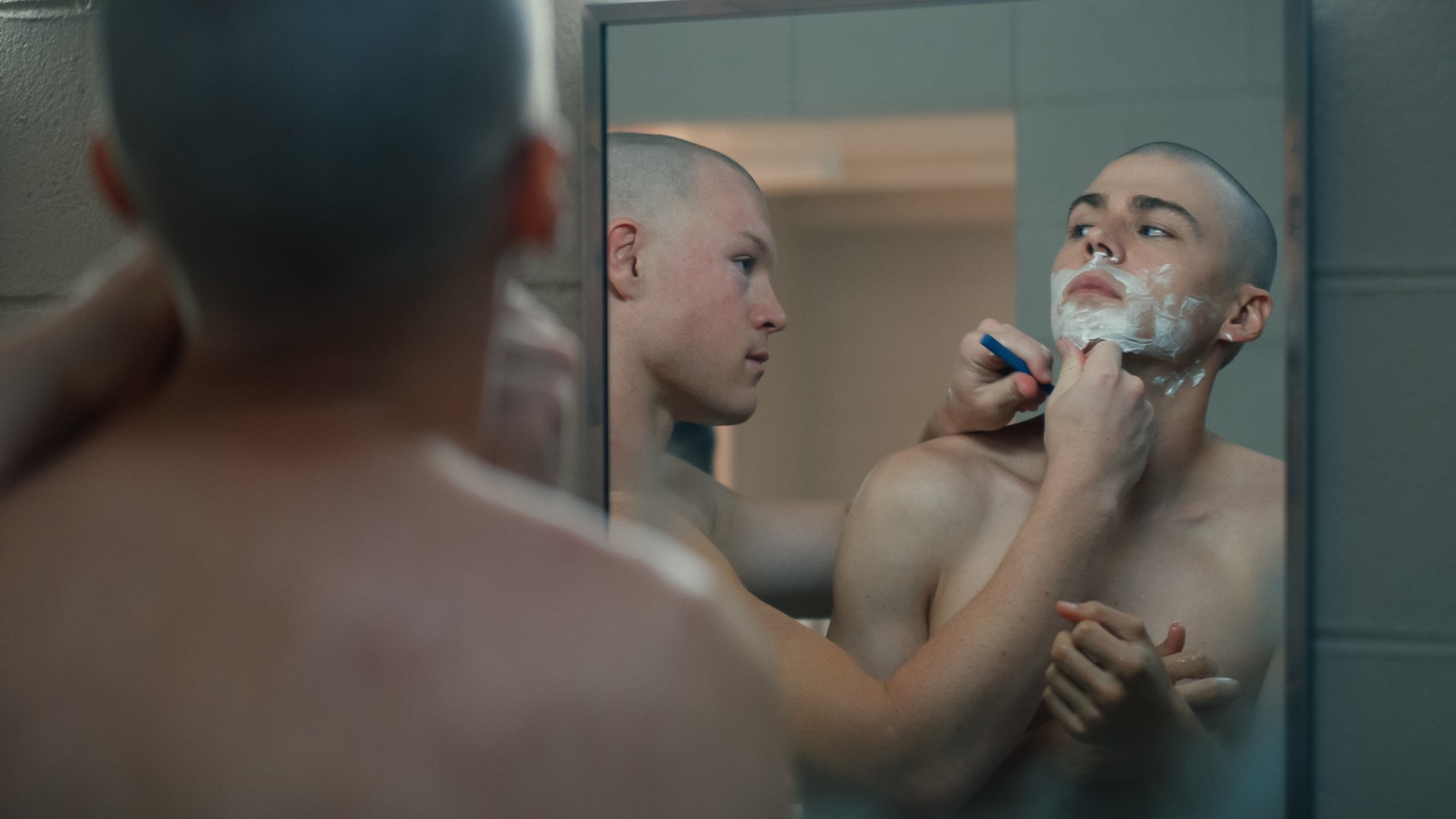 Angus O’Brien's character shaving Miles Heizer's character's face in a mirror in Netflix show Boots