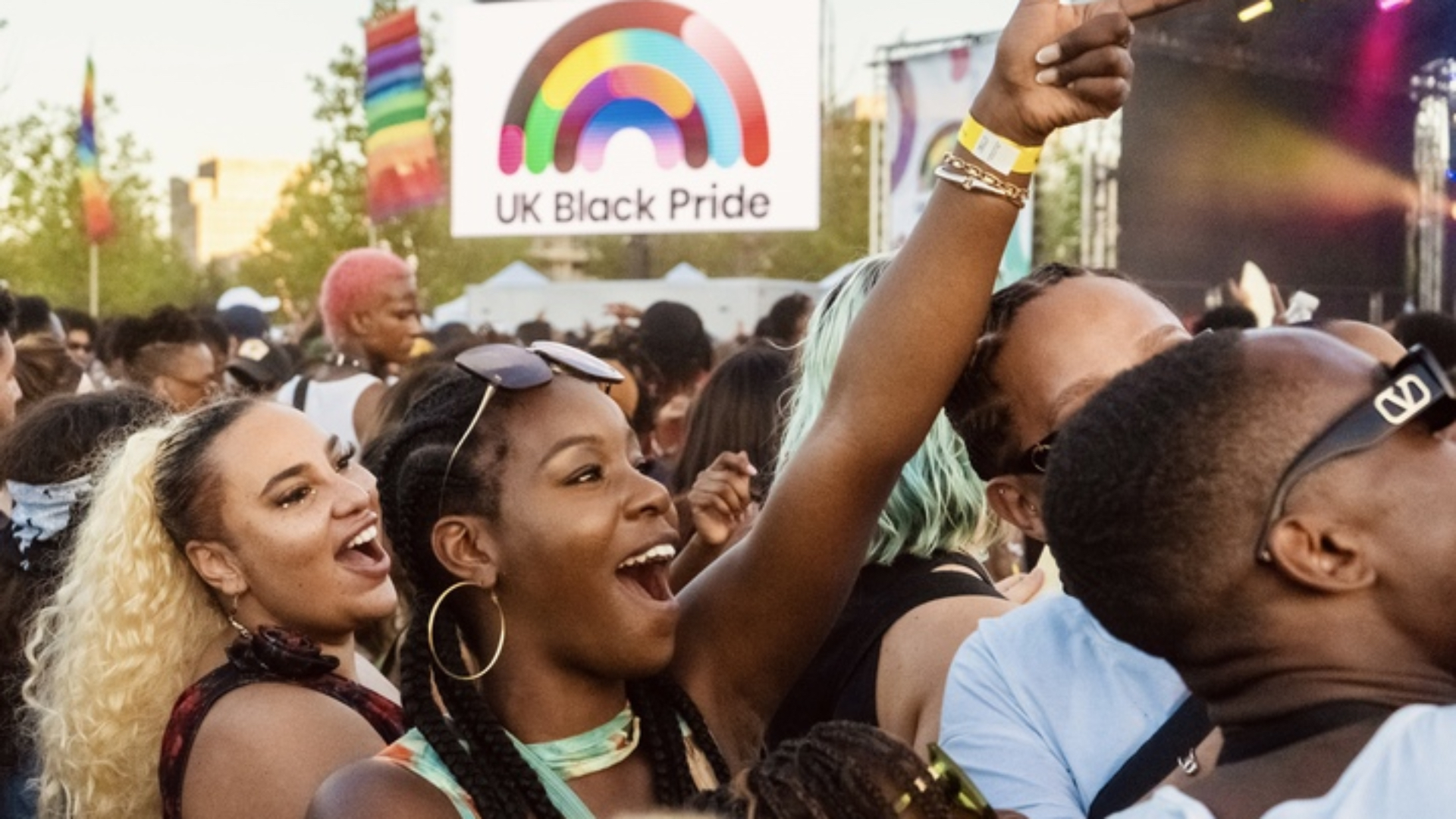 A girl reaching out in a crowed of bi-racial LGBTQ+ people and allies at UK Black Pride