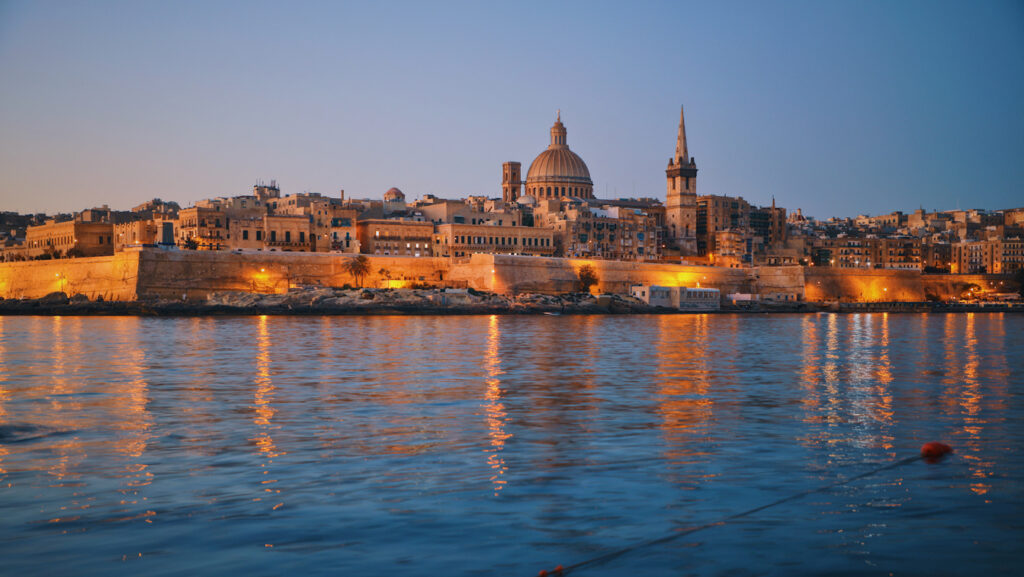 A night time view of Malta's capital with waterin front of it