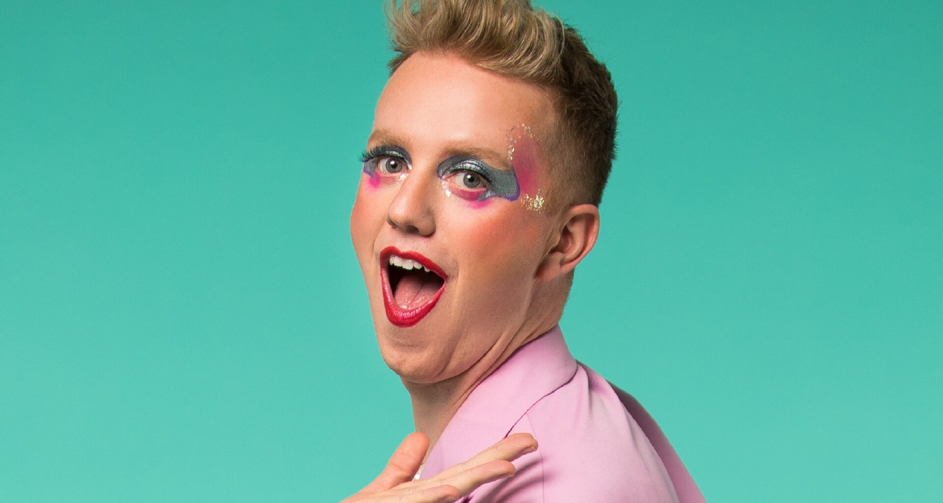 a head and shoulders of James Barr against a green backdrop with make-up on