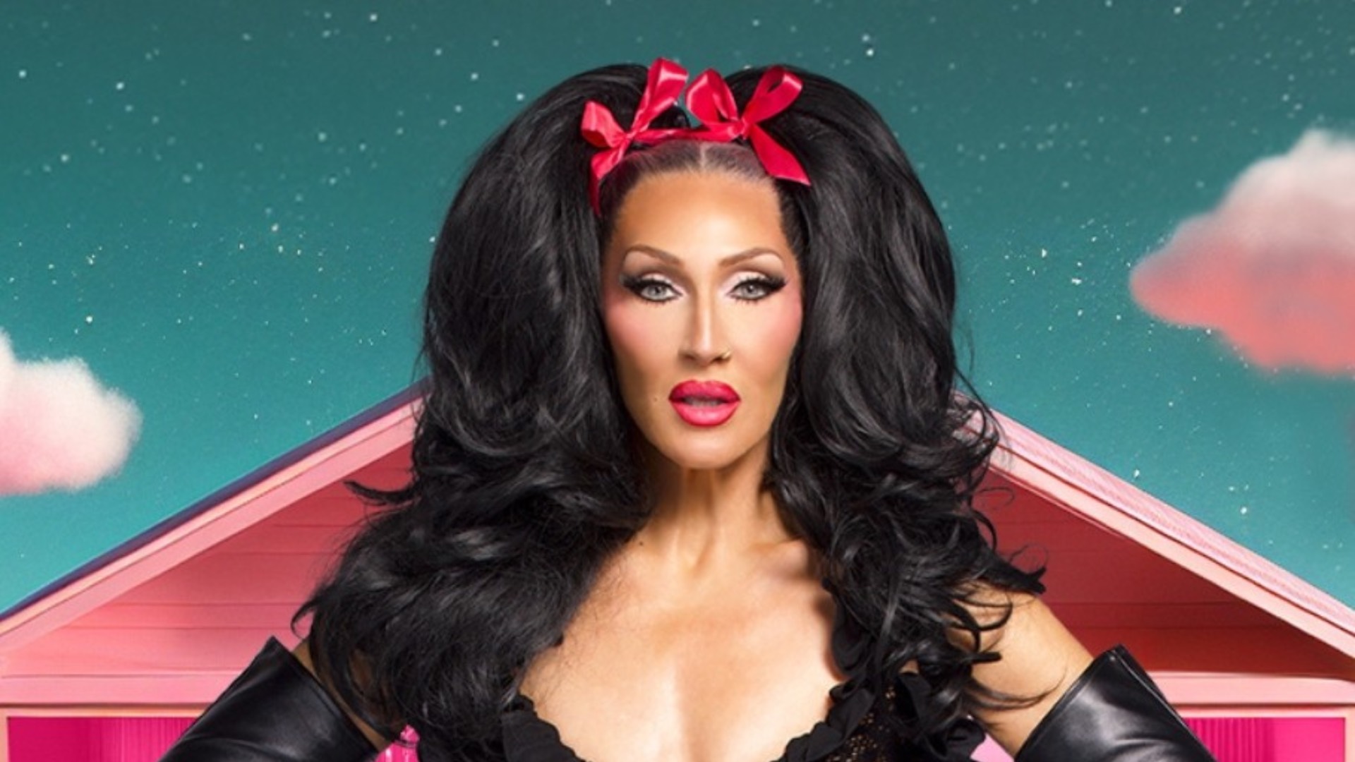 Michelle Visage wearing a pink bow, a black lace top and leather gloves