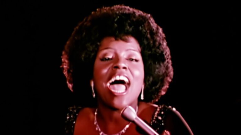 Gloria Gayner singing into a microphone with an afro