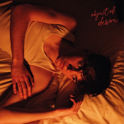 Fred Roberts lying in bed wearing a vest in warm lighting
