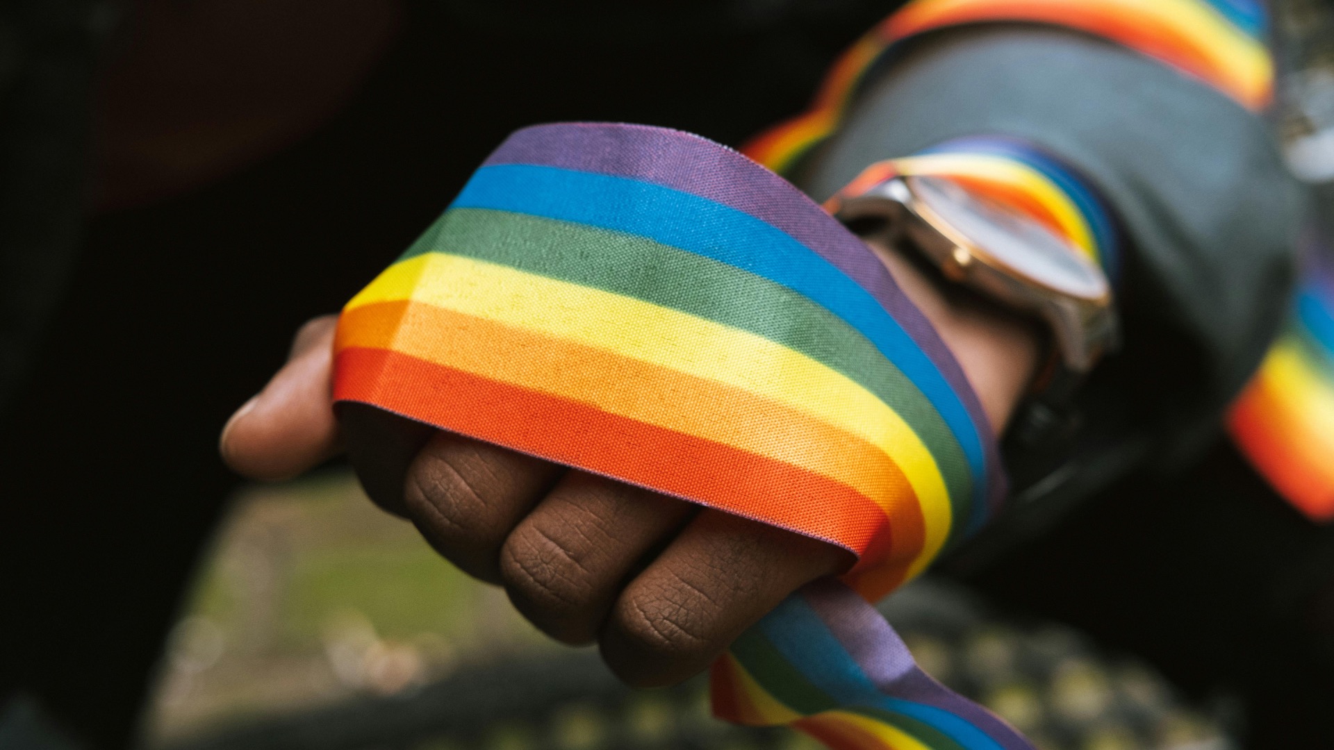 A hand clutching a distressed pride flag