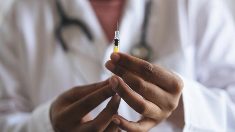 Doctor holding a syringe wearing white coat