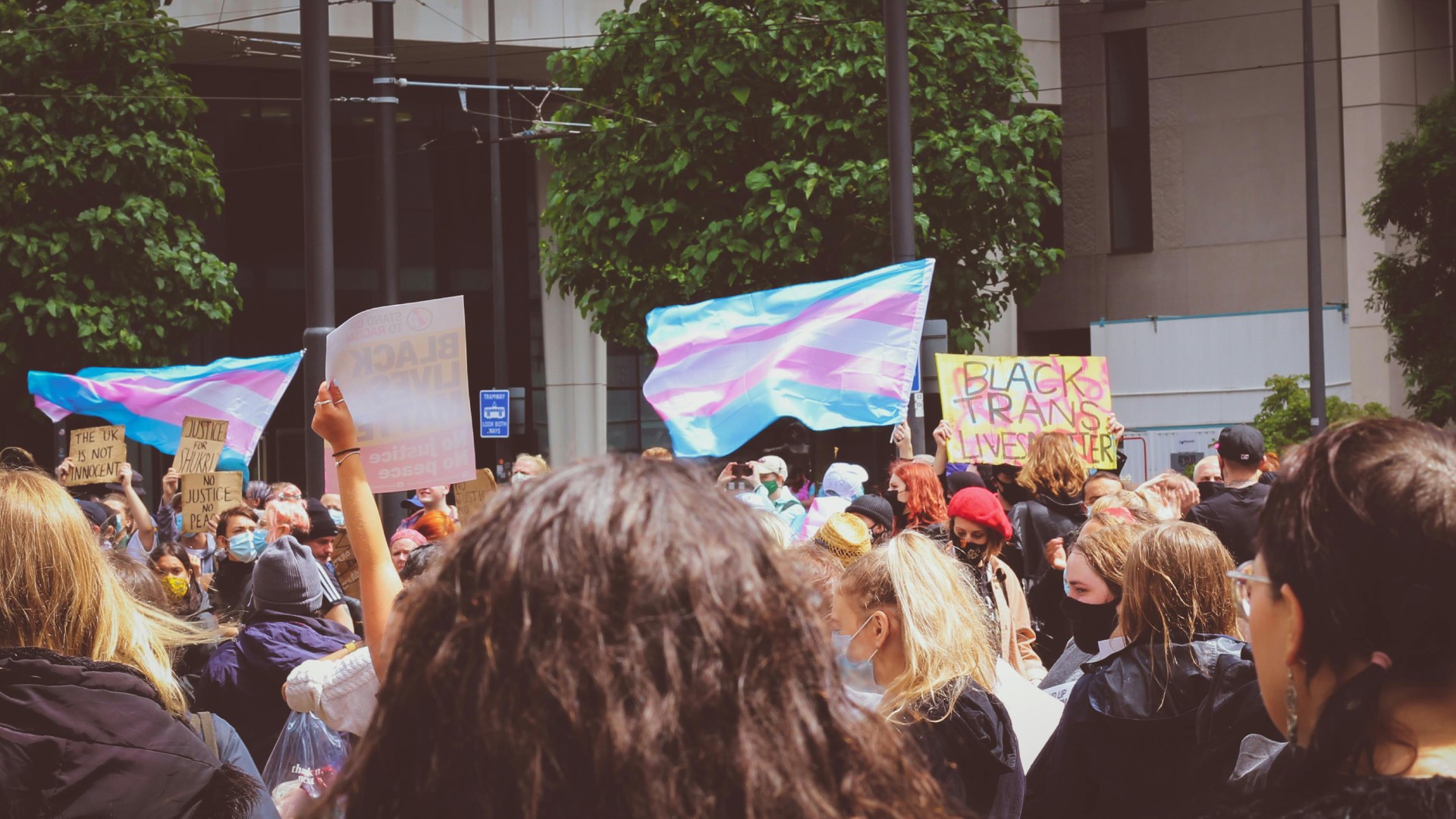 a trans pride flag flying above marchers