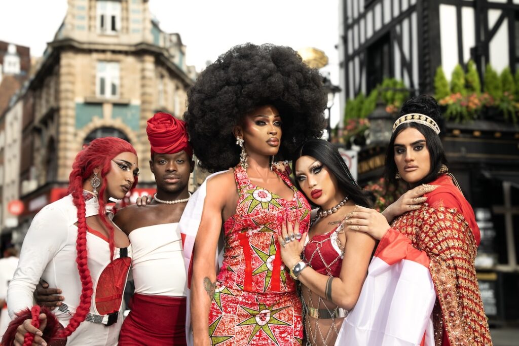 Drag queens dressed in red and white cuddled together in a sign of unity