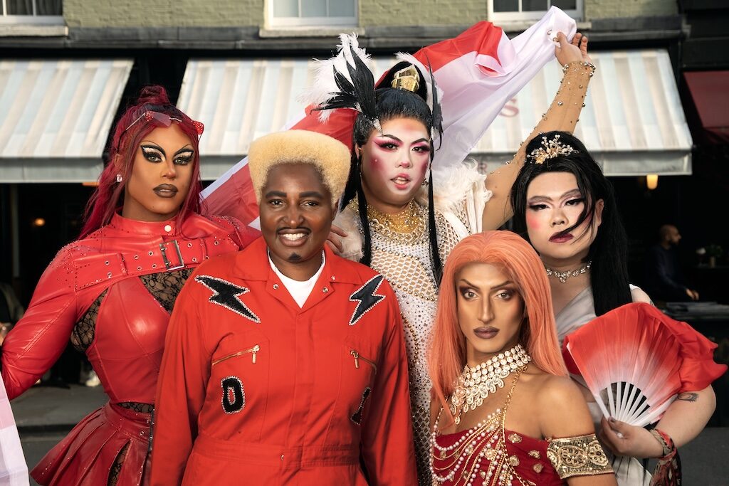 Drag king and queens dressed in red and white waving St George's flags