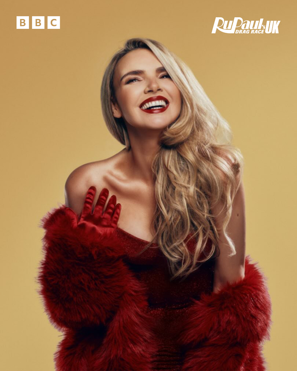 Nadine Coyle in a fur red coat smiling wearing red lipstick