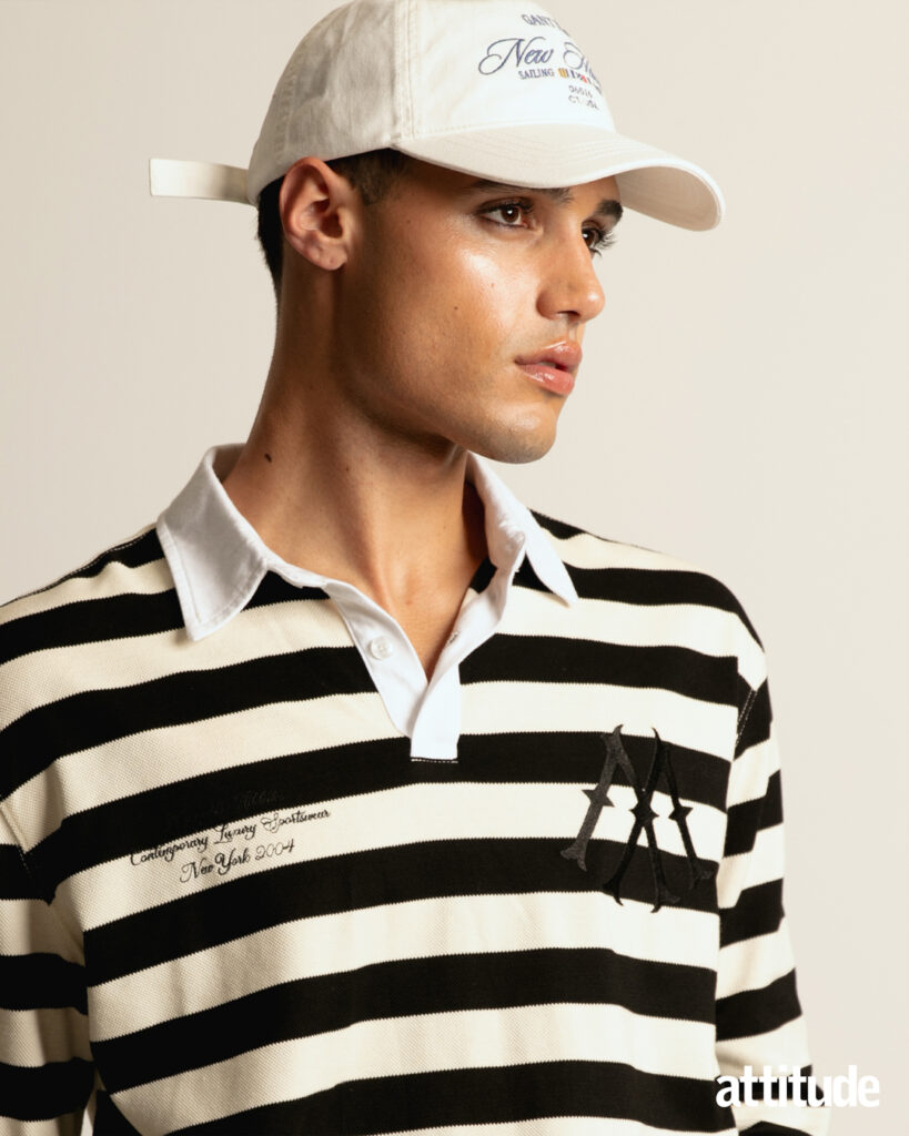 A model wears a cap and black and white striped rugby shirt in Attitude's menswear editorial. 