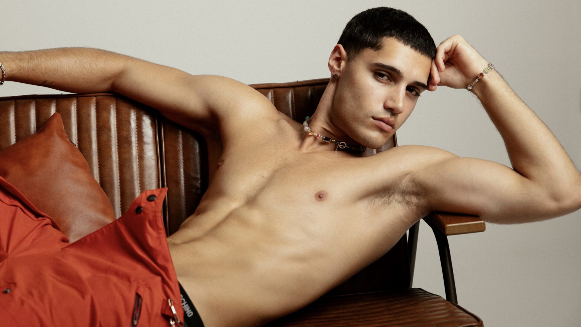 A shirtless models relaxed on a sofa in Attitude's Main Fashion editorial shoot 'Soft Power'.