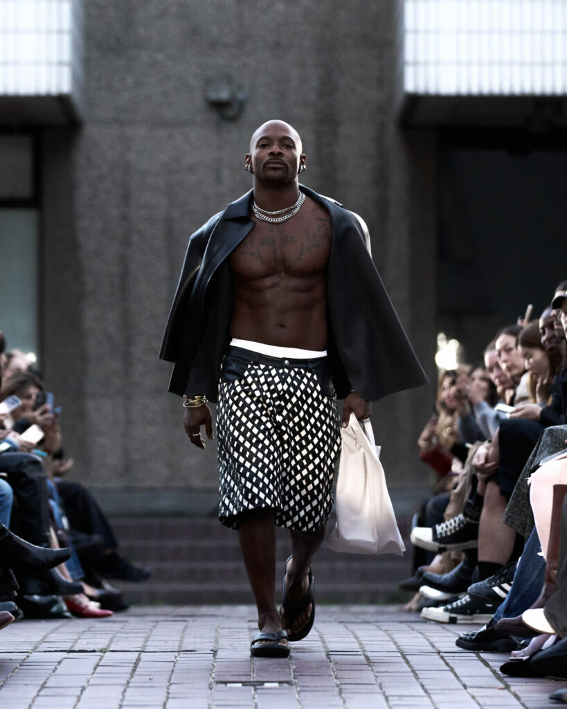 A model wears an open latex shirt from the HARRI Spring/Summer 2026 collection