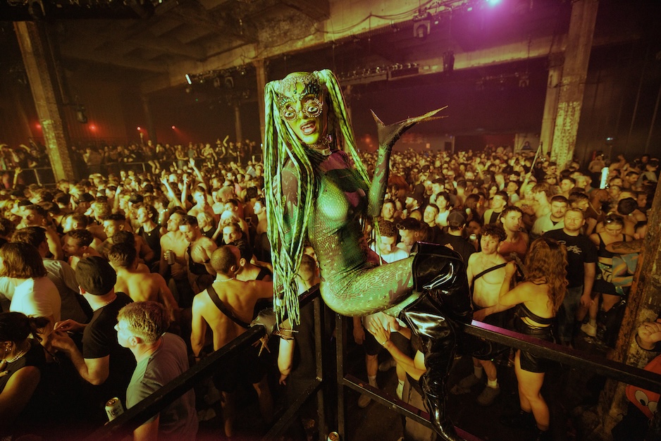 Performer sat in a railing in a crowd of shirtless men