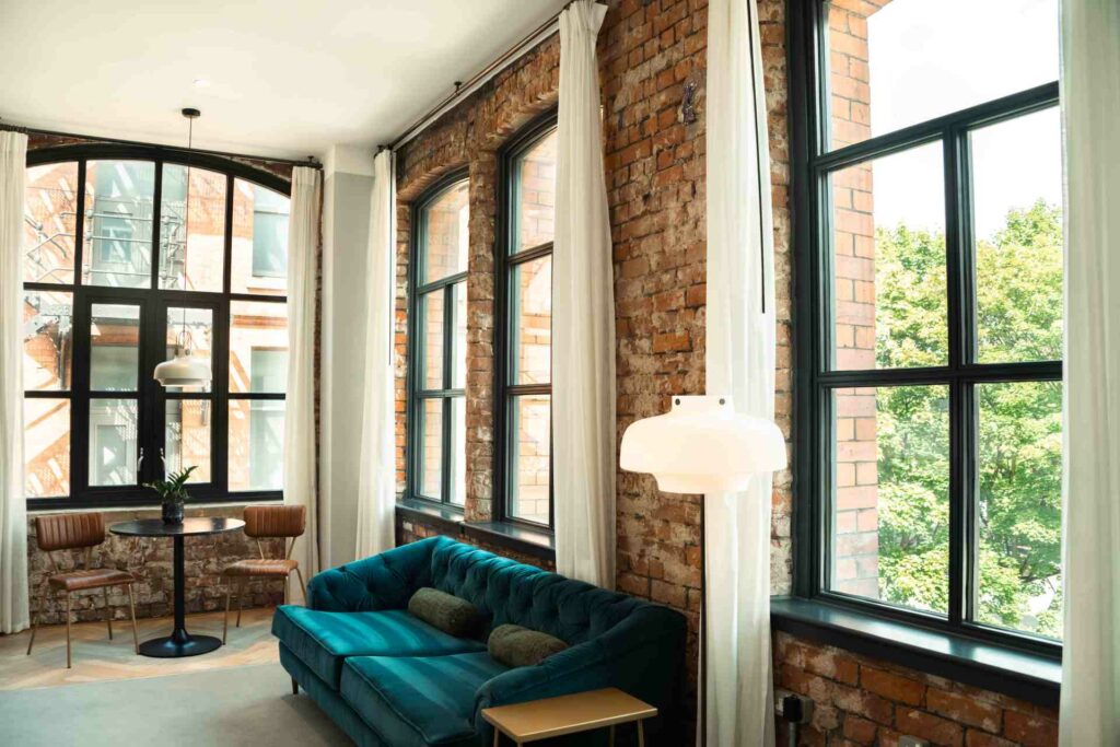 Internal shot of a hotel room with Brick walls and a blue sofa