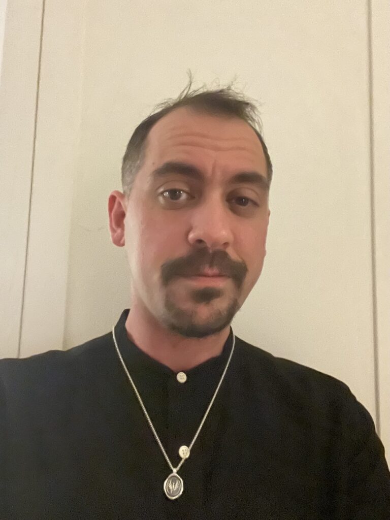 Leng in a black t-shirt with a gold chain, moustache