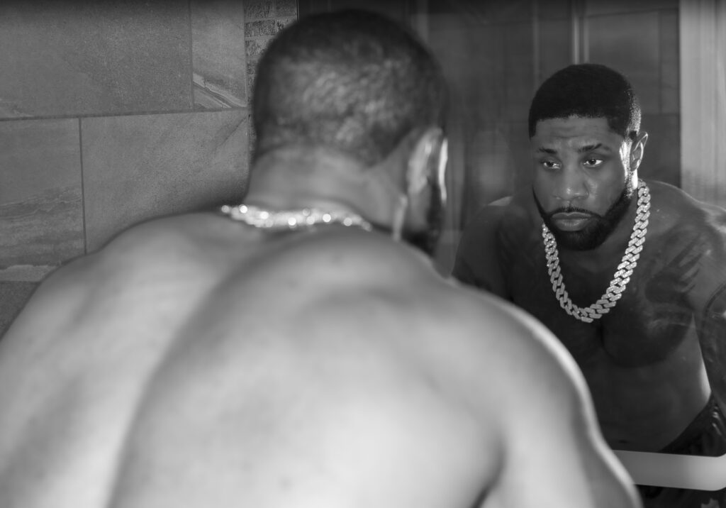 "Before the mirror, strength and vulnerability meet in quiet collision. The reflection is not performance but confrontation, an honest encounter with selfhood beyond categories. The mirror becomes both shield and confession, rejecting simplification. This portrait affirms that queer existence is not singular but fluid, layered, and unconfined, holding space for identities that resist easy definition."