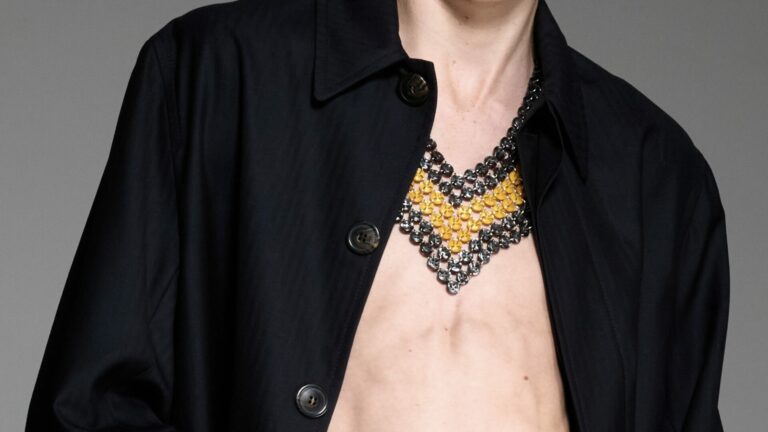 A close-up of a model wearing a black overcoat and chainlink necklace from Stefan Cooker Spring/Summer 2026.