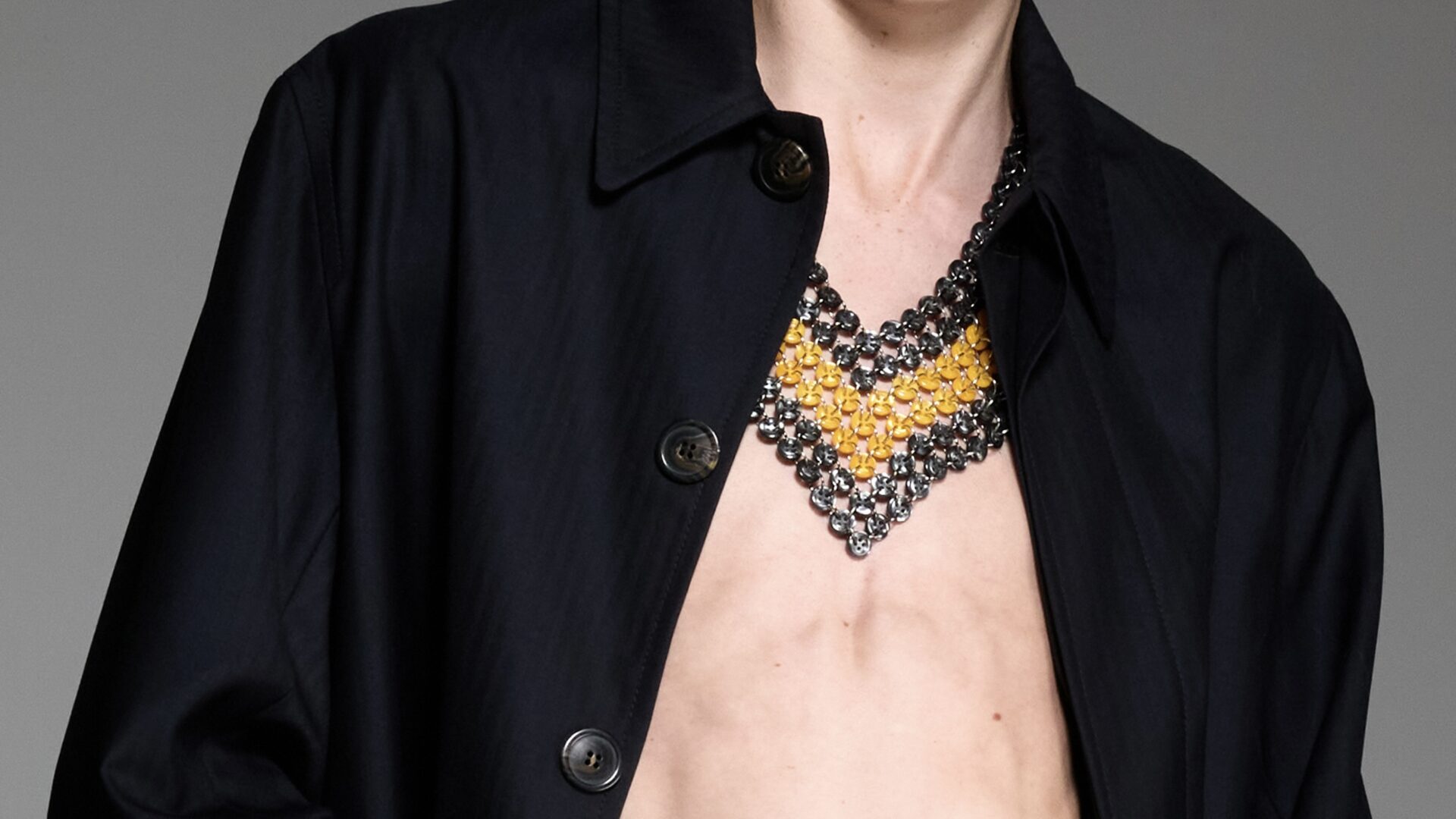 A close-up of a model wearing a black overcoat and chainlink necklace from Stefan Cooker Spring/Summer 2026.