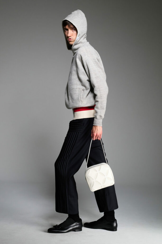 A model wears a hoodie and black trousers from the Stefan Cooke Spring/Summer 2026 collection.