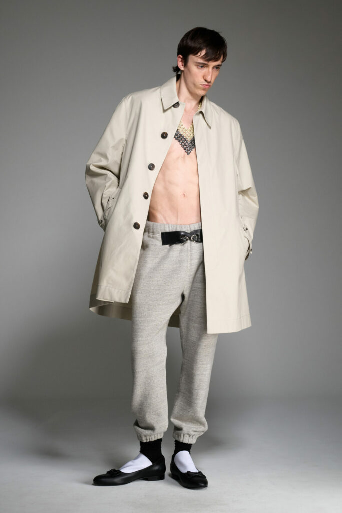 A model wears a trench coat and grey sweat pants from the Stefan Cooke Spring/Summer 2026 collection.