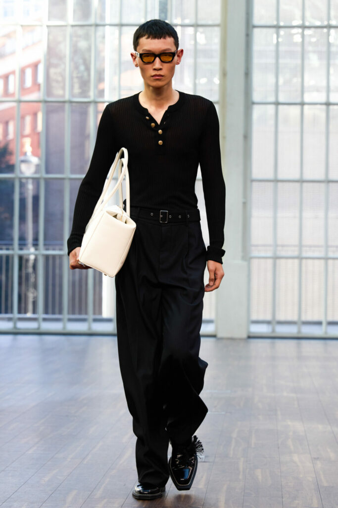 A model wears a black henley from the Mithridate Spring/Summer 2026 collection.