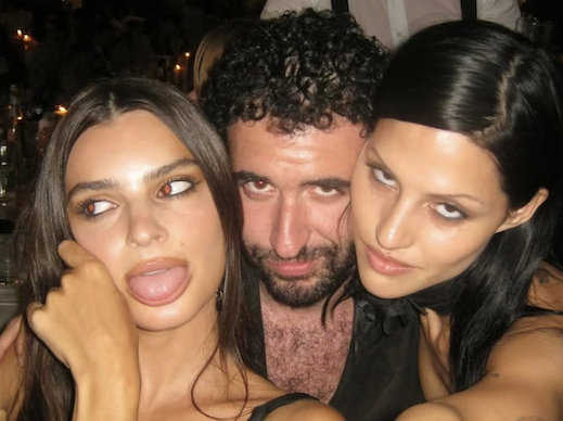 Jordan Firstman smirking in the middle of Emily Ratajkowski and Gabbriette posing for the camera 