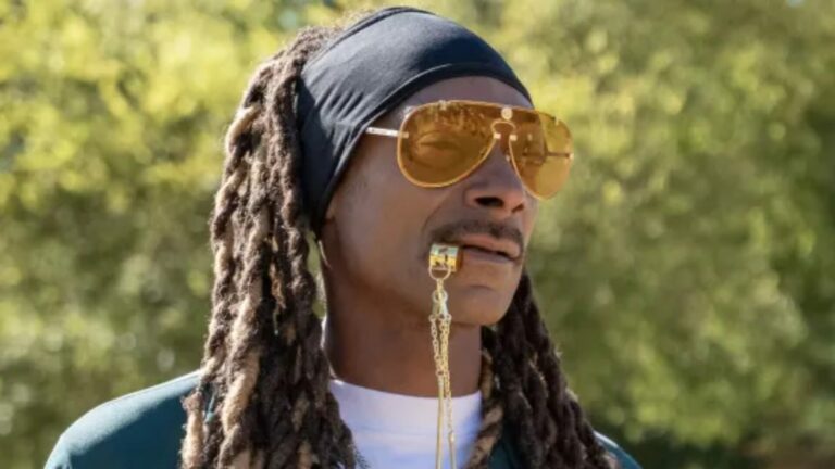 Snoop Dogg wearing yellow sunglasses, a bandana blowing a gold whistle