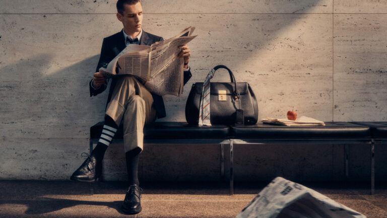 A model wearing Thom Browne sits next to his Bolton Bag.