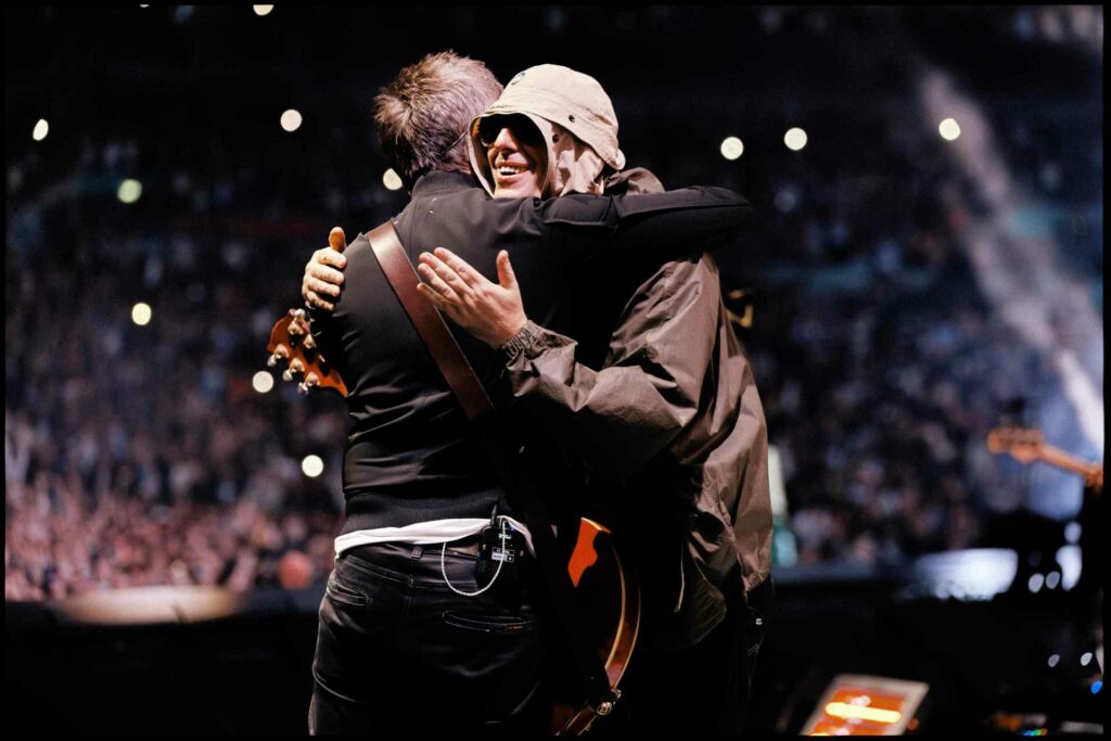 Noel and Liam Gallagher hugging on stage at Wembley Stadium