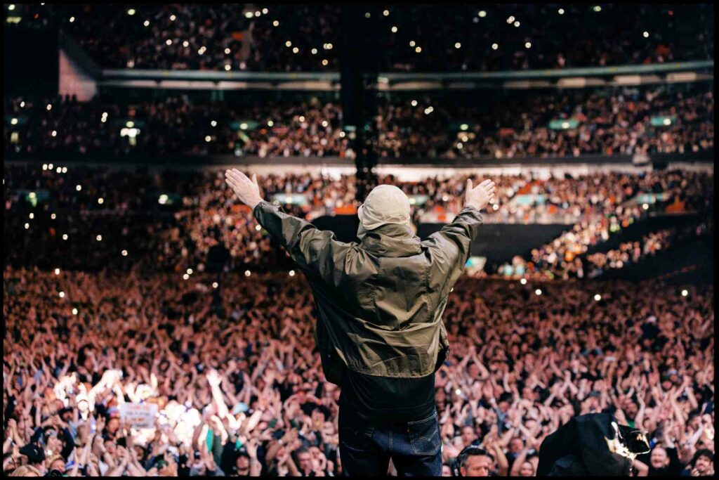 Liam Gallagher holding his arms up over the crowd at Wembley Stadium