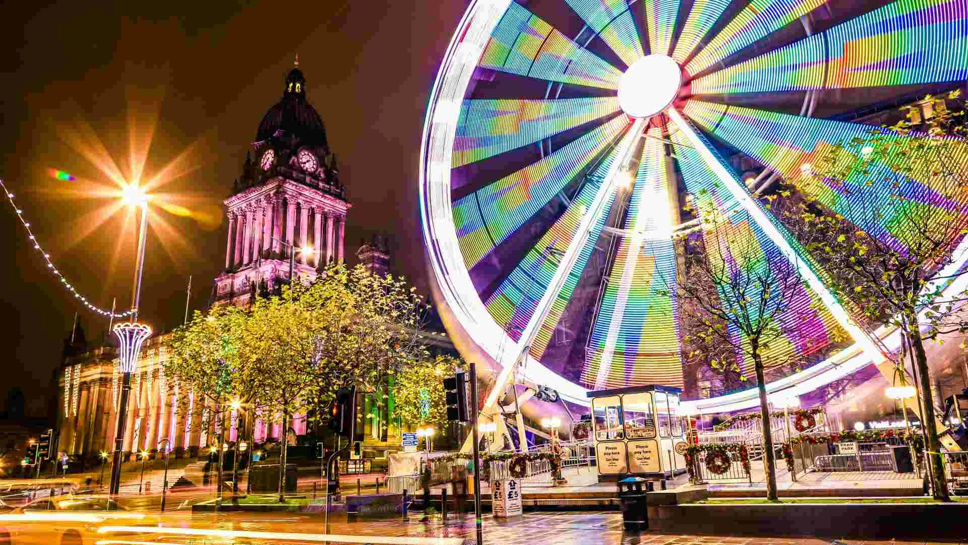 Night view of the Leeds Ferris wheel with trees of buildings behind