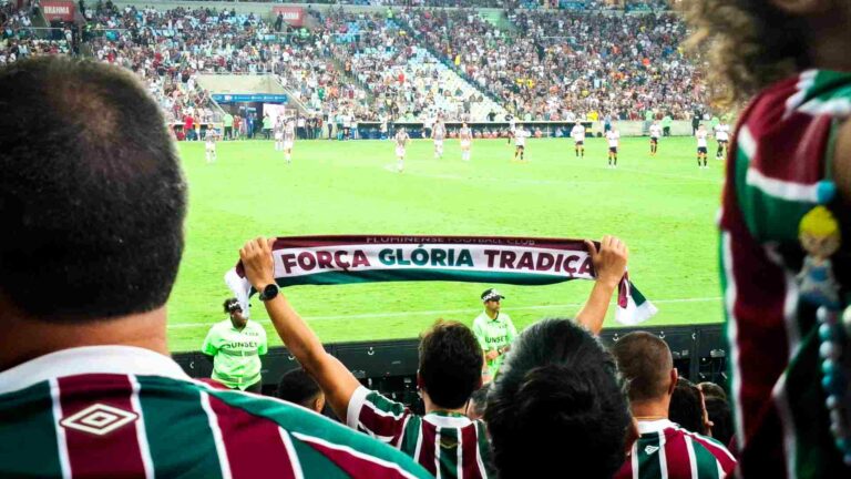 Football fans inside a football stadium waving scarves and banners