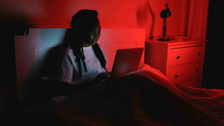 A woman sitting in bed using a laptop