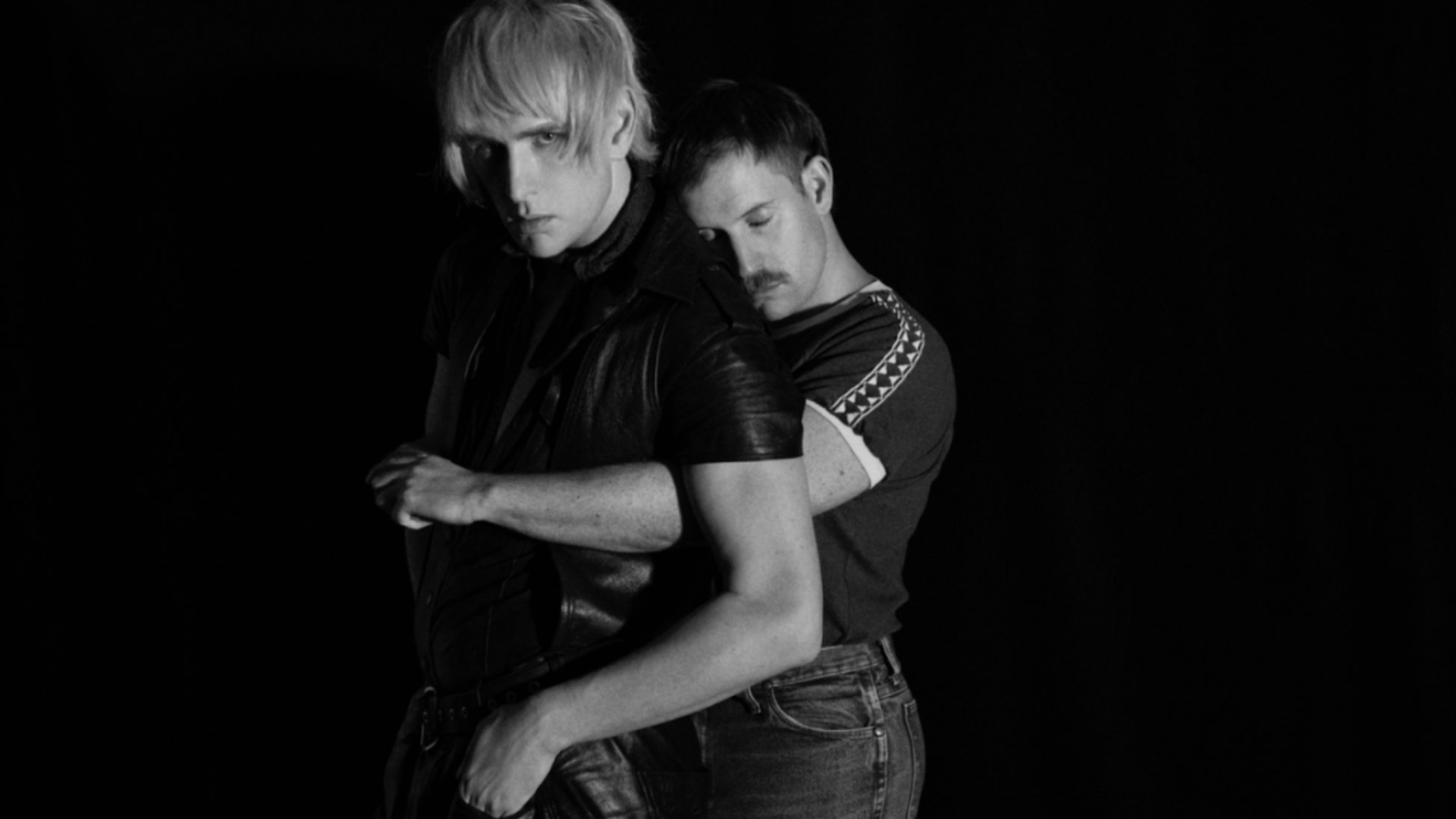 black and white picture of Patrick Wolf and Rhumba Club embracing him from behind