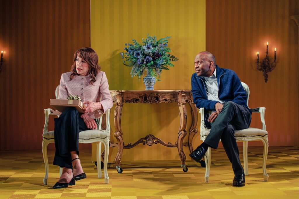 Rachel Crowl as Catherine (Kate), Princess of Wales; K. Todd Freeman as William, Prince of Wales sitting in a living room