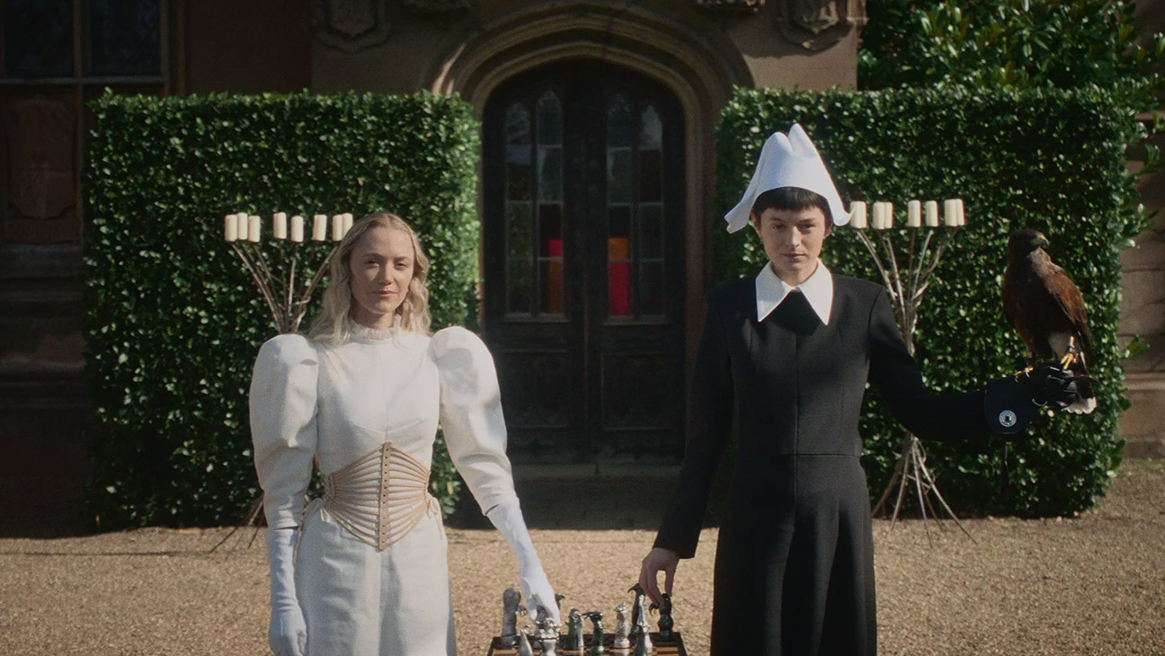 Maika Monroe and Emma Corrin in 100 Nights of Hero, in period dress and playing chess