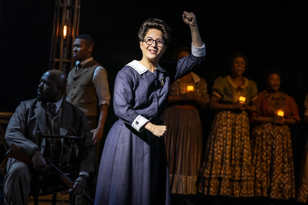 Woman cheering with Ragtime cast holding candles behind her