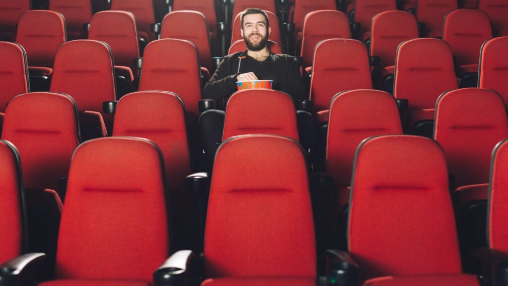 A man sitting in a theatre eating popcorn
