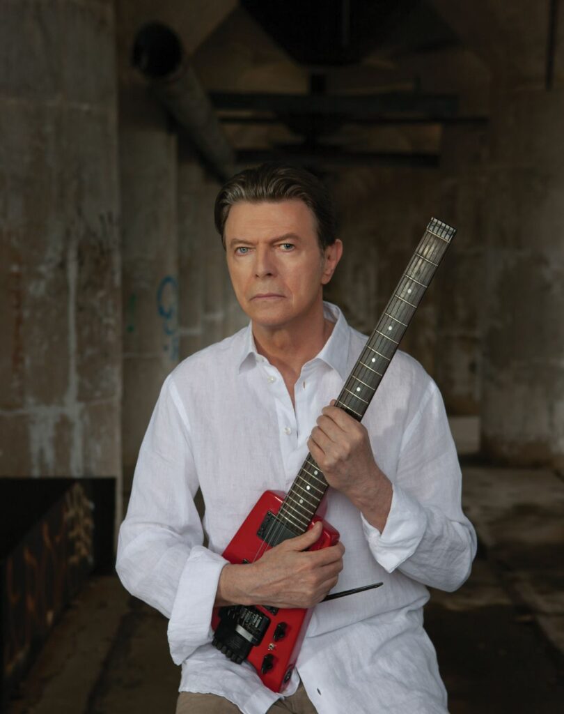 David Bowie holding a red guitar