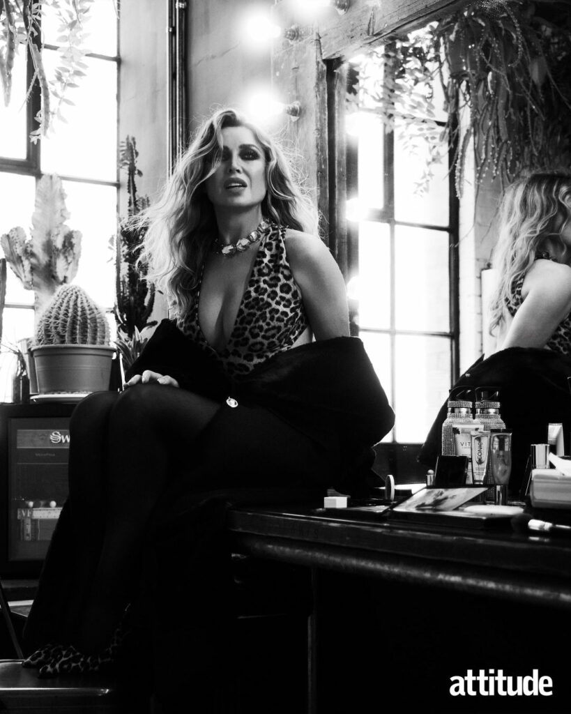 Black and white image of Dannii Minogue wearing an animal print top sitting on a makeup table in front of a mirror